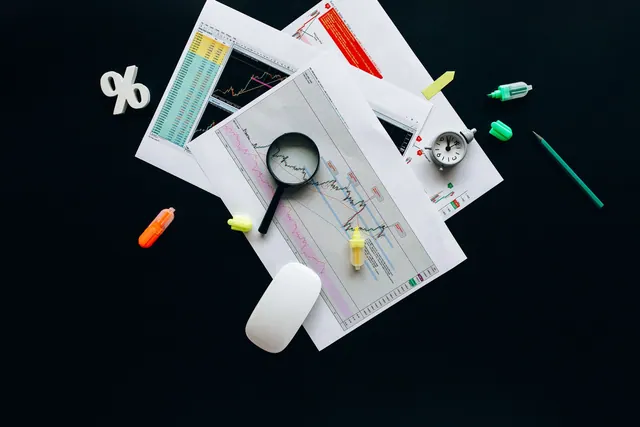 Overhead view of an office desk with financial documents, a magnifying glass, and stationery items, suggesting business analysis. How to audit a poll or survey story before you cite it