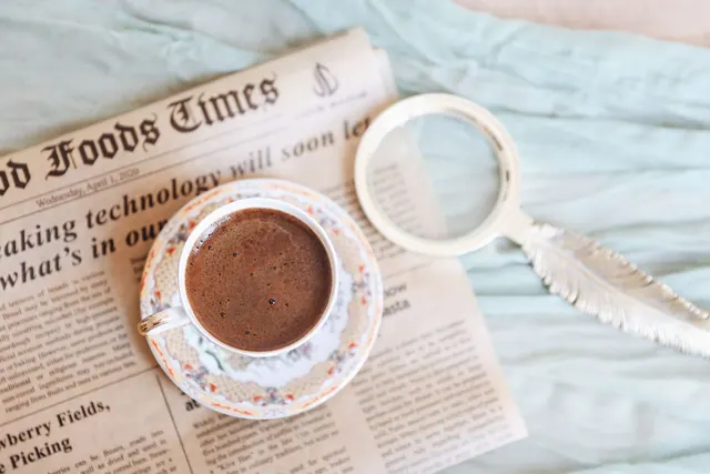A cup of coffee with a newspaper and magnifying glass, perfect for a relaxing morning read. Common source-evaluation mistakes and how to fix them