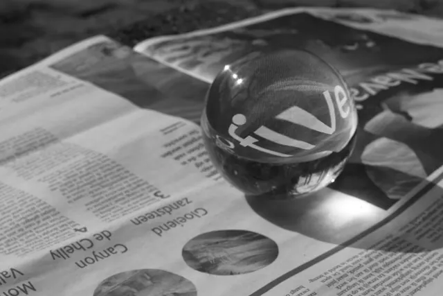 A glass sphere magnifies text on a newspaper in a close-up black and white photo. How to geolocate and chronolocate visual media