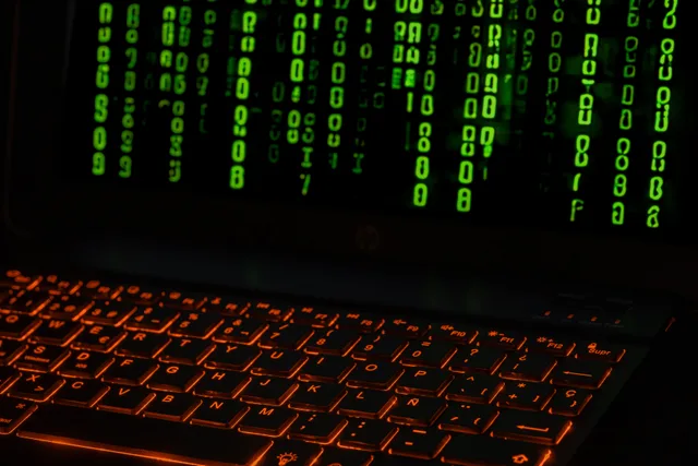 A laptop keyboard with orange backlight displaying green digital code symbols. How to verify suspected AI images, video, and audio