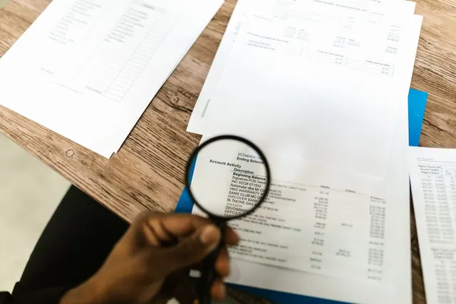 Close-up of hand using magnifying glass to review documents. Ideal for financial themes. Social account identity signals compared